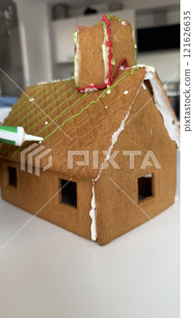Decorating a Homemade Gingerbread House with Green and White Frosting Details Decorating a Homemade Gingerbread House with Green and White Frosting Details 121626635