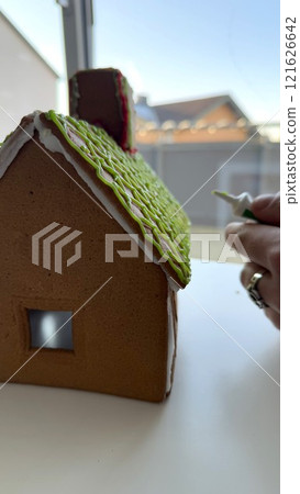 Close-Up of Decorating a Gingerbread House with Frosting and Icing Details Close-Up of Decorating a Gingerbread House with Frosting and Icing Details 121626642