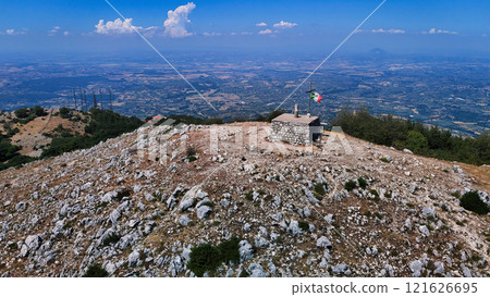 Italian flag waving on the top of a mountain with a breathtaking view Italian flag waving on the top of a mountain with a breathtaking view 121626695