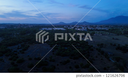 Cityscape turning on lights at dusk with mountains in background Cityscape turning on lights at dusk with mountains in background 121626706