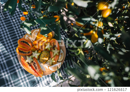 Colorful tropical fruit platter enjoyed in a garden setting on a sunny day 121626817