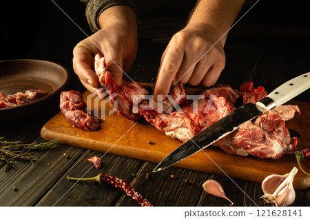 Hands expertly dissect various cuts of meat on a wooden board, showcasing a blend of skillful technique and culinary passion. The rustic atmosphere amplifies the artistry of butchery Hands expertly dissect various cuts of meat on a wooden board, showcasing a blend of skillful technique and culinary passion. The rustic atmosphere amplifies the artistry of butchery 121628141