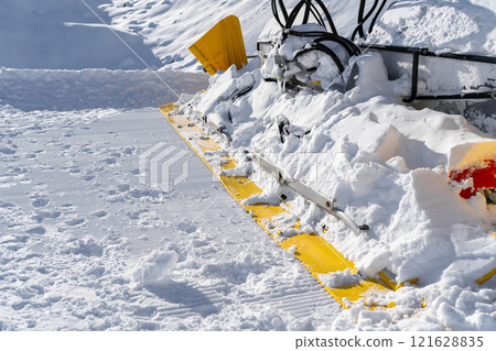 Close-up of snow plow blade clearing snow on ski slope Close-up of snow plow blade clearing snow on ski slope 121628835