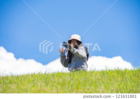 young Asian woman takes a selfie against the background of the sky and green lawn young Asian woman takes a selfie against the background of the sky and green lawn 121631801