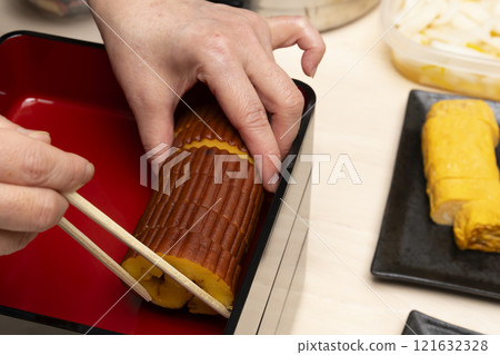 用筷子將禦節料理裝入重箱中。 121632328