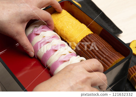 Packing New Year's food into a tiered box with chopsticks Packing New Year's food into a tiered box with chopsticks 121632332