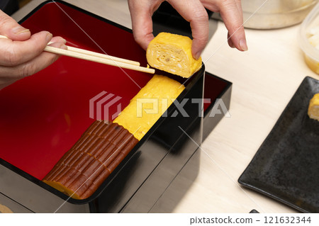 Packing New Year's food into a tiered box with chopsticks 121632344