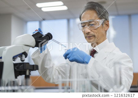 Research/experiment image: Senior man in a white coat working with test tubes and droppers 121632617