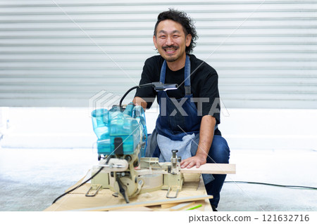 Portrait of a craftsman using an electric saw 121632716