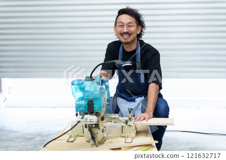 Portrait of a craftsman using an electric saw 121632717