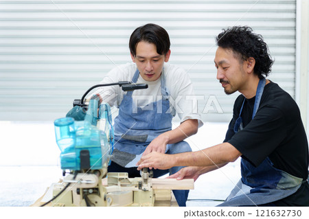 Craftsman and apprentice using electric saw Craftsman and apprentice using electric saw 121632730