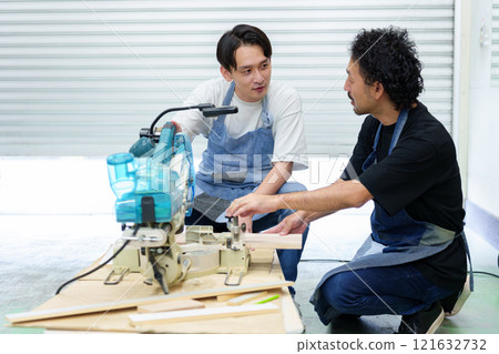 Craftsman and apprentice using electric saw Craftsman and apprentice using electric saw 121632732