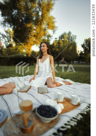 Couple enjoys a picnic in a park during golden hour with homemade treats 121633439