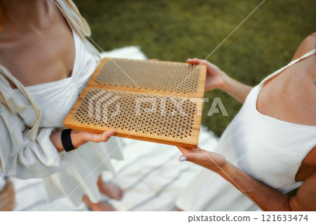 Two friends enjoying a game with wooden board on a sunny day outdoors Two friends enjoying a game with wooden board on a sunny day outdoors 121633474