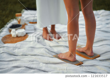 Relaxing wellness session on a picnic blanket in a serene outdoor setting Relaxing wellness session on a picnic blanket in a serene outdoor setting 121633517