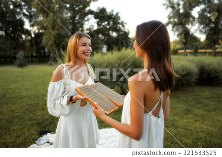 Friends enjoy a sunny afternoon with honeycomb in a green park 121633525