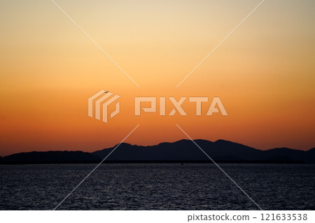 Sunset over the sea with a flying airplane in the sky. 121633538