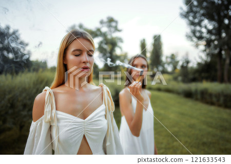 Two women enjoying a peaceful moment in nature during the late afternoon Two women enjoying a peaceful moment in nature during the late afternoon 121633543