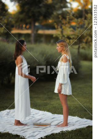 Two women conversing outdoors in serene green setting during golden hour Two women conversing outdoors in serene green setting during golden hour 121633582