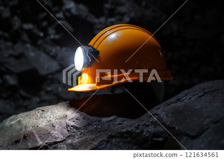Yellow miners safety helmet with head lamp on the coal mining background.ai generative 121634561