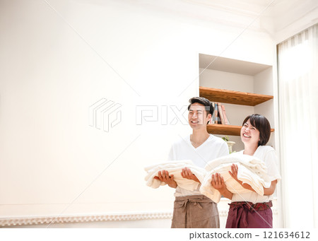 A couple smiling and talking while carrying laundry A couple smiling and talking while carrying laundry 121634612