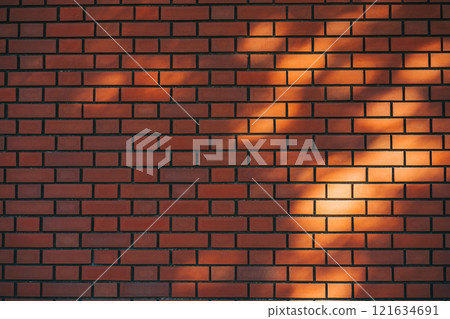 Brick wall illuminated by sunlight filtering through the trees Brick wall illuminated by sunlight filtering through the trees 121634691