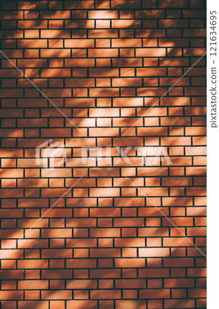 Brick wall illuminated by sunlight filtering through the trees 121634695