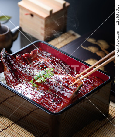 A sizzling Japanese food cut of steaming eel rice being picked up with chopsticks A sizzling Japanese food cut of steaming eel rice being picked up with chopsticks 121635019