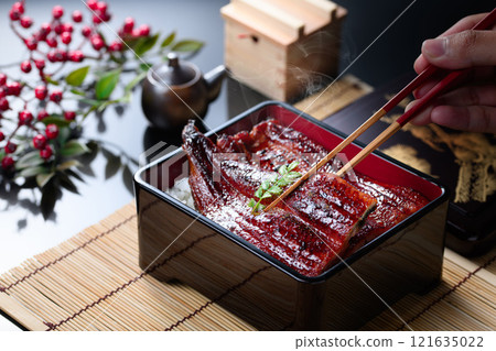 用筷子夾起熱氣騰騰的鰻魚飯，滋滋作響的日本料理 121635022