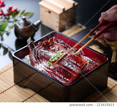 用筷子夾起熱氣騰騰的鰻魚飯，滋滋作響的日本料理 121635023