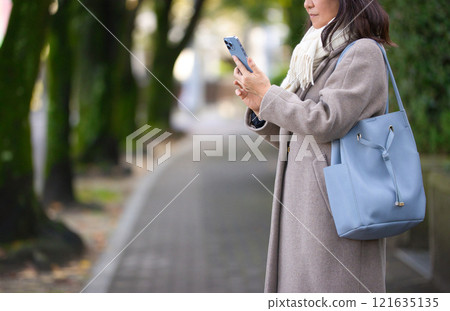 穿著外套在城裡散步的中年婦女 121635135