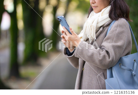 穿著外套在城裡散步的中年婦女 121635136