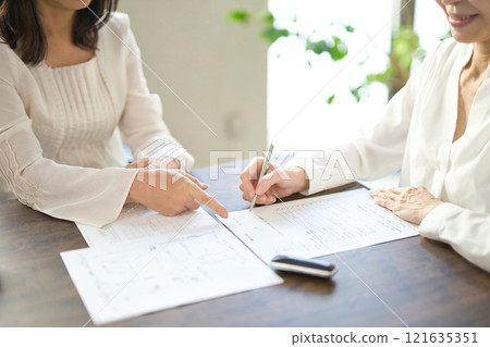 The hands of two women signing a real estate contract 121635351