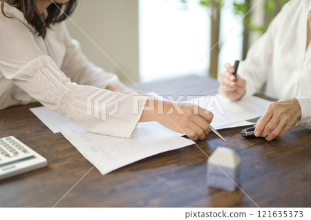 The hands of two women signing a real estate contract The hands of two women signing a real estate contract 121635373