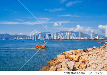 Large rocks on the background of the beach, Vietnamese boats, mountains and high-rise buildings in Nha Trang, Vietnam. Large rocks on the background of the beach, Vietnamese boats, mountains and high-rise buildings in Nha Trang, Vietnam. 121635770