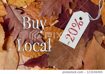 Tag with the word buy is hanging from a pile of leaves 121636494