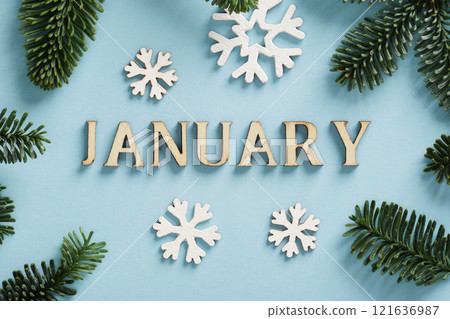The word January in English is made of wooden letters, surrounded by spruce branches and snowflake ornaments 121636987