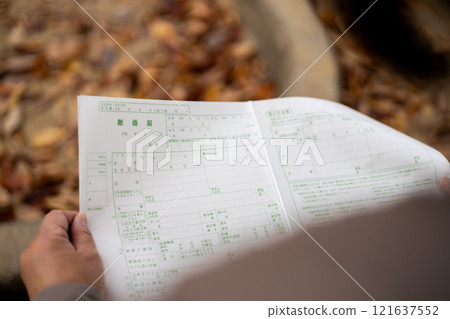 一名中年婦女坐在公園的長椅上,看著離婚文件。 一名中年婦女坐在公園的長椅上,看著離婚文件。 121637552