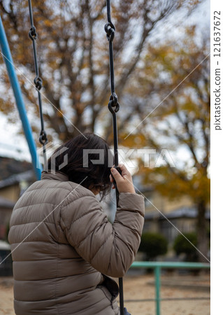 一名中年婦女在空蕩蕩的公園裡獨自盪鞦韆的後視圖 一名中年婦女在空蕩蕩的公園裡獨自盪鞦韆的後視圖 121637672