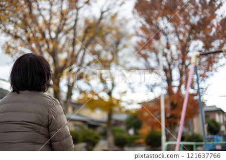 Back view of a middle-aged woman sitting in a park and daydreaming 121637766