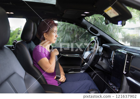 Senior woman sitting on car seat and fasten seatbelt before drive. 121637902