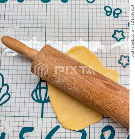 wooden rolling pin on table a flattened ball of dough on a patterned baking mat. High quality photo 121638914