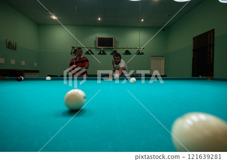 A group of people gathered in the billiard room to play and have fun. A group of friends plays billiards. People relax and play billiards. 121639281