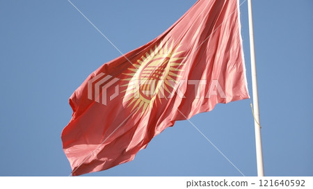 Kyrgyzstan flag is waving in Ala-Too Square against the blue sky Kyrgyzstan flag is waving in Ala-Too Square against the blue sky 121640592