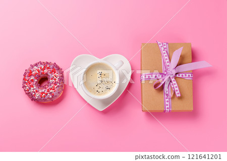 A vibrant donut and a coffee cup on a heart-shaped saucer, perfect for a Valentines Day card 121641201