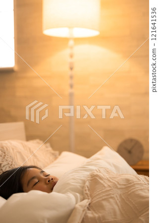 A child sleeping in a bed in a room with indirect lighting 121641536