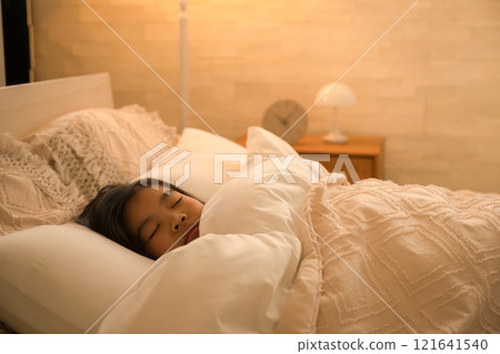 A child sleeping in a bed in a room with indirect lighting A child sleeping in a bed in a room with indirect lighting 121641540