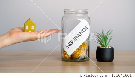 Housing insurance concept. Home, property and life Insurance. Mortgage, loan. A miniature house on a hand and a jar of coins. Business and finance 121641601