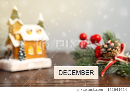 December block against the background of a Christmas tree and a house with snow. Concept of the beginning of a new winter season December block against the background of a Christmas tree and a house with snow. Concept of the beginning of a new winter season 121641614