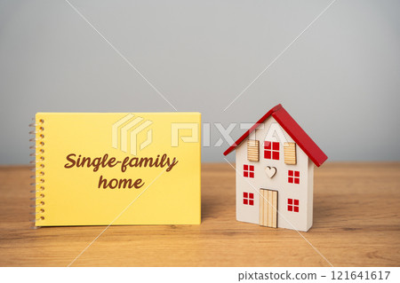 Single-family home concept. Standalone residential building designed to house one family or household. A notebook with an inscription near a miniature house. Real estate Single-family home concept. Standalone residential building designed to house one family or household. A notebook with an inscription near a miniature house. Real estate 121641617